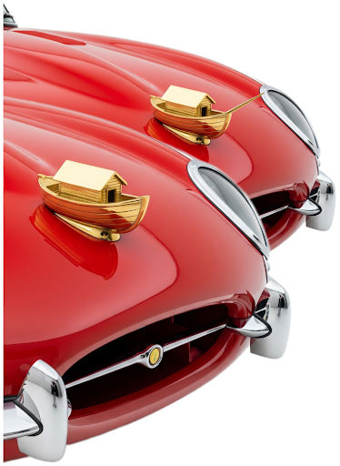 Tongue-in-cheek image of two identical golden car hood ornaments, except the one in the foreground (the modern) is lacking a bowsprit